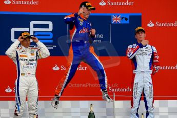 World © Octane Photographic Ltd./Chris Enion. GP2 British GP, Silverstone, Sunday 30th June 2013. Race 2 winner Jon Lancaster - Hilmer Motorsport celebrates on the podium with James Calado and Rio Haryanto. Digital Ref : 0732ce1d9562