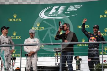 World © Octane Photographic Ltd. Gerard Butler drinks from the race boot of Red Bull Racing's Daniel Ricciardo whilst Mercedes' Lewis Hamilton and Nico Rosberg watch. Sunday 23rd October 2016, F1 USA Grand Prix Podium, Austin, Texas – Circuit of the Americas (COTA). Digital Ref :1750LB1D4716